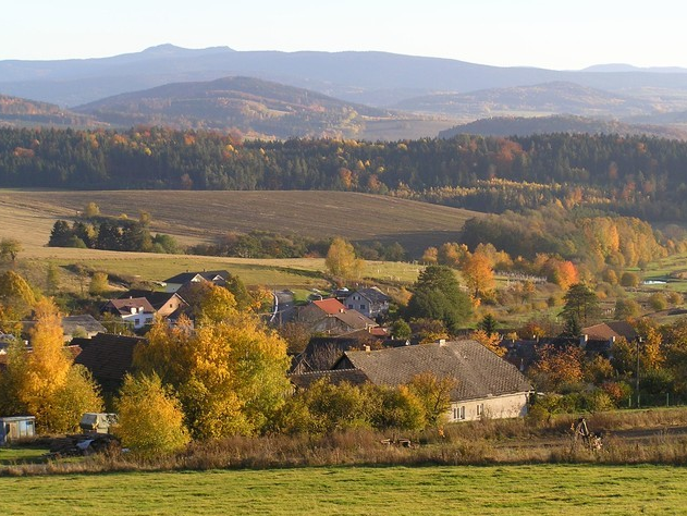 Obec v údolí obklopeném zalesněnými vrchy